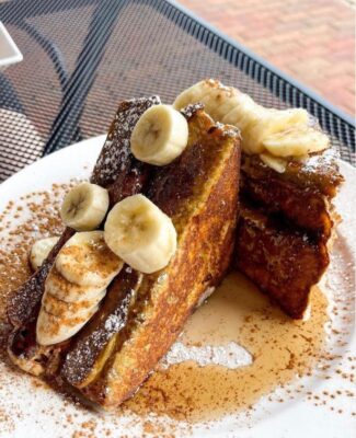 Challah French toast covered in bananas and syrup from Sabrina's Cafe